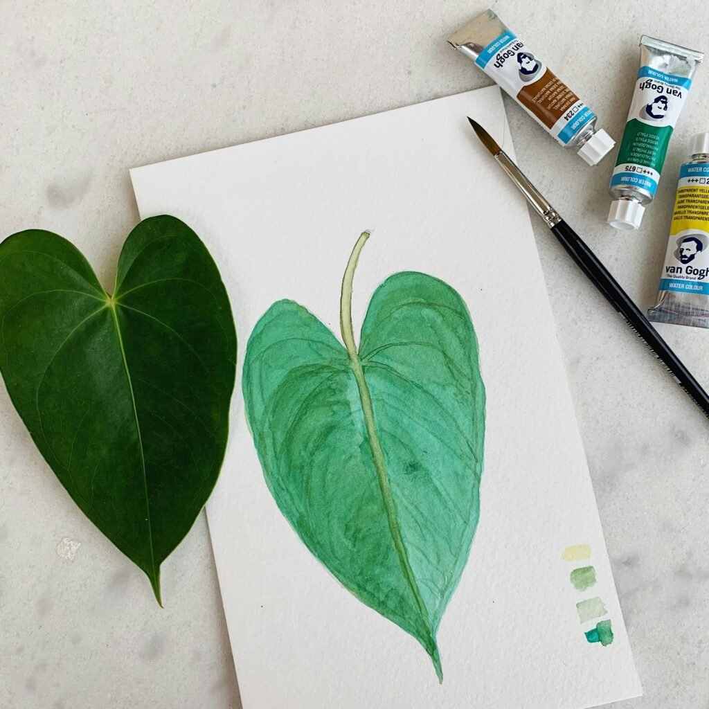 A realistic watercolor painting of a leaf with paints and brushes.